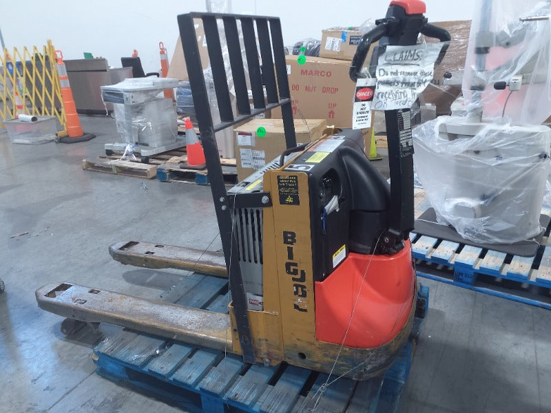 An electric pallet jack with an orange and black color scheme, positioned on a pallet in a warehouse setting.